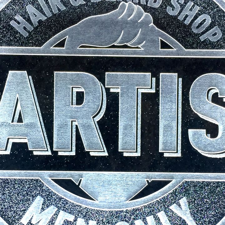Detail van een logo gegraveerd in donkere plexi